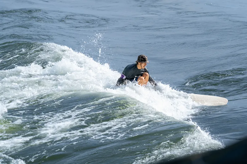Un surfeur accroupi file sur la vague dans une gerbe d'écume