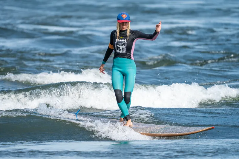 Une surfeuse en casquette et legging turquoise glisse sur un longboard en bois