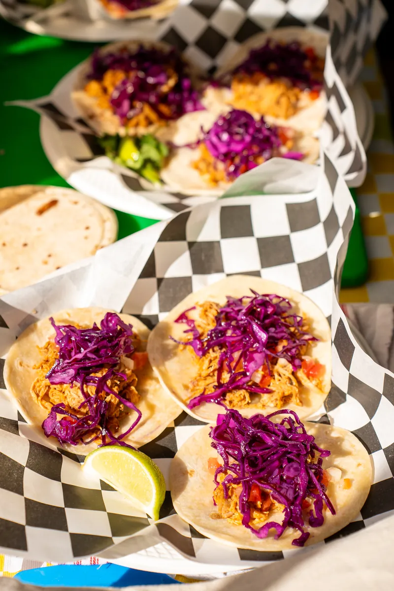 Des tacos garnis de chou mauve servis dans des barquettes à damier
